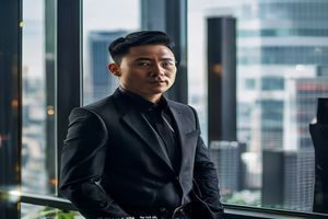 磁力猫创始人陈远航的工作照，身着深色商务休闲装站在办公室落地窗前，神情专注自信，背景为城市高楼轮廓，体现创业者的理性与远见